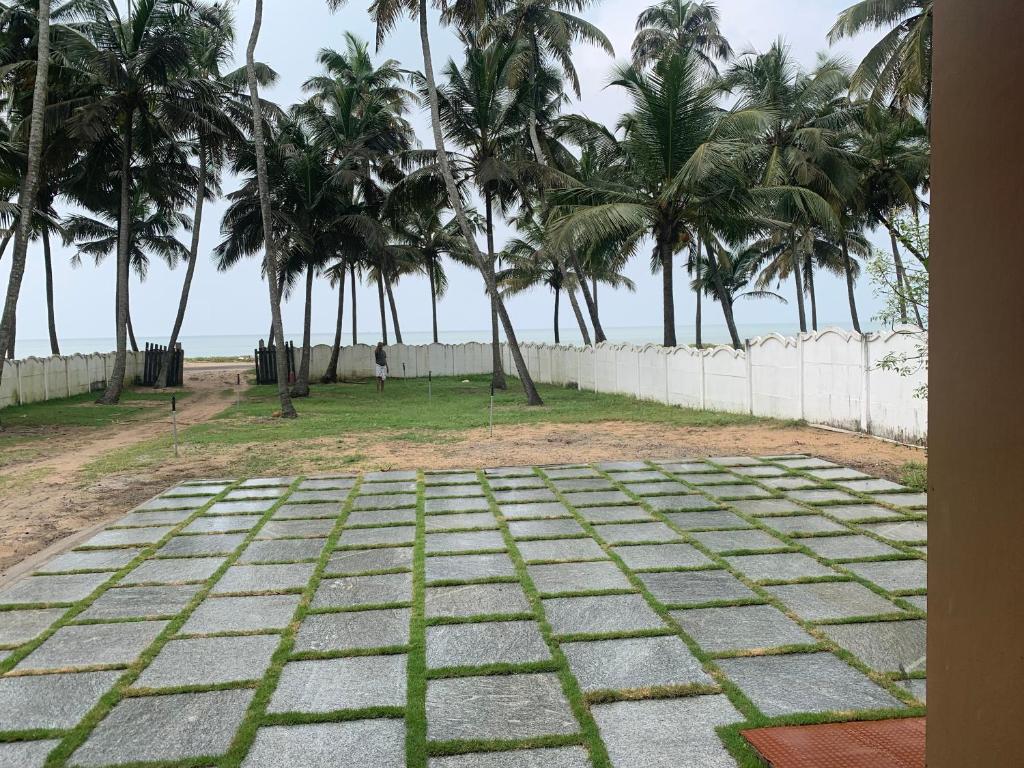 a stone pathway with palm trees in the background at Casa Ganesha beach residence in Irimbranallūr