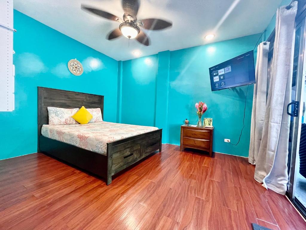 - une chambre bleue avec un lit et un ventilateur de plafond dans l'établissement Ngermid Oasis- 2 BD Master Suite, à Koror