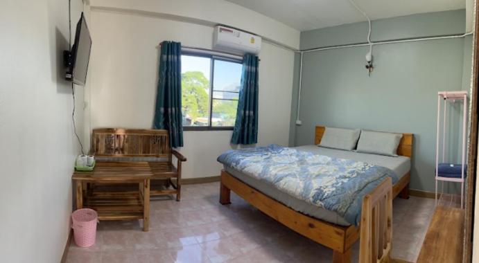 um quarto com uma cama, uma secretária e uma janela em หอพักบ้านชูใจ em Phitsanulok