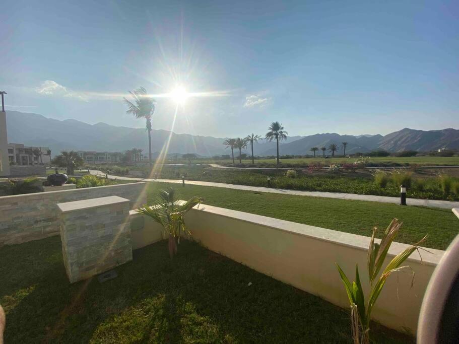 a view of the mountains from a house with the sun at Lovely studio apartment inside Jebel Sifah resort in As Sīfah