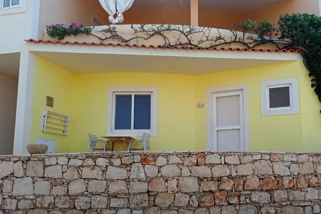 a yellow house with a table and chairs on a wall at Appartamento BICA. Stella Maris Exclusive in Calheta Do Maio