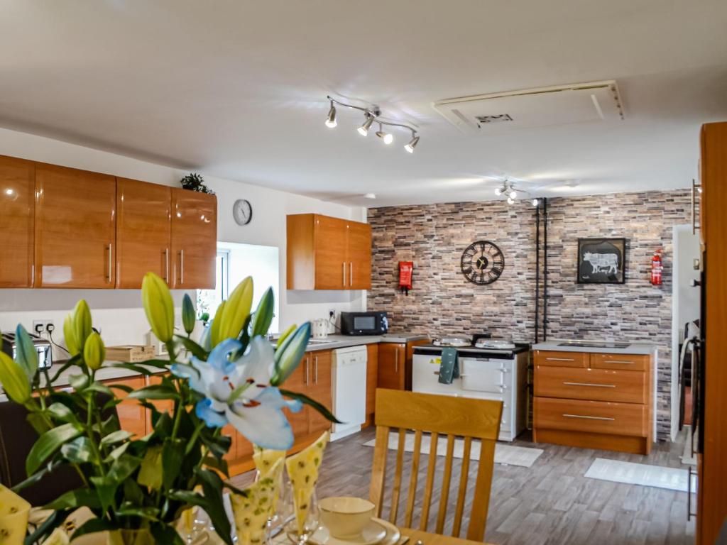 a kitchen with a table and a brick wall at Muirston Farmhouse in Ochiltree