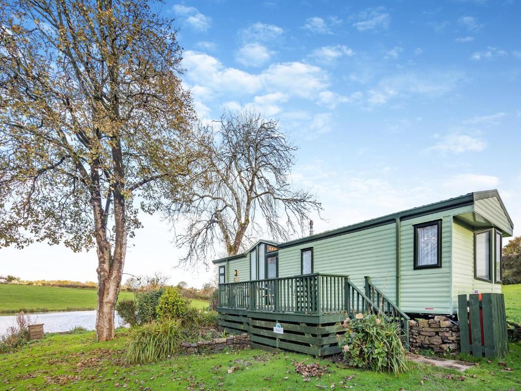 una casa verde con portico e albero di Hafod Caravan - Uk45717 a Brynteg