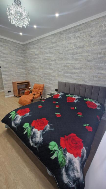 a bed with a black blanket with red roses on it at Апартаменты в ЖК Мерей in Karagandy