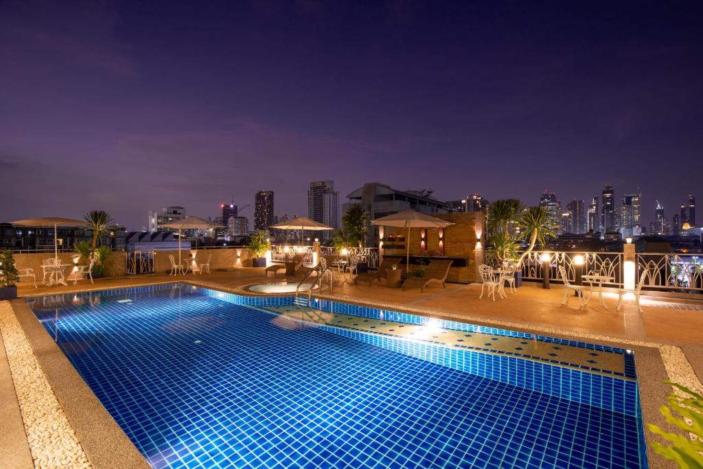 una piscina por la noche con vistas al perfil urbano en Capitel Rama 4, en Bangkok