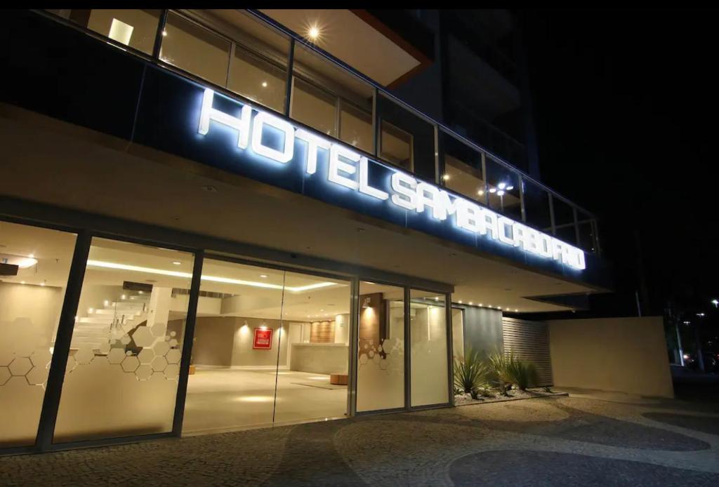 a building with a neon sign on the side of it at Hotel Samba Cabo Frio Flat in Cabo Frio