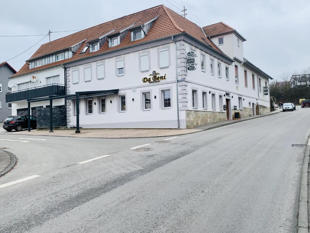 ein weißes Gebäude an der Straßenseite in der Unterkunft Hotel Pizzeria Da Beni in Kochersteinsfeld