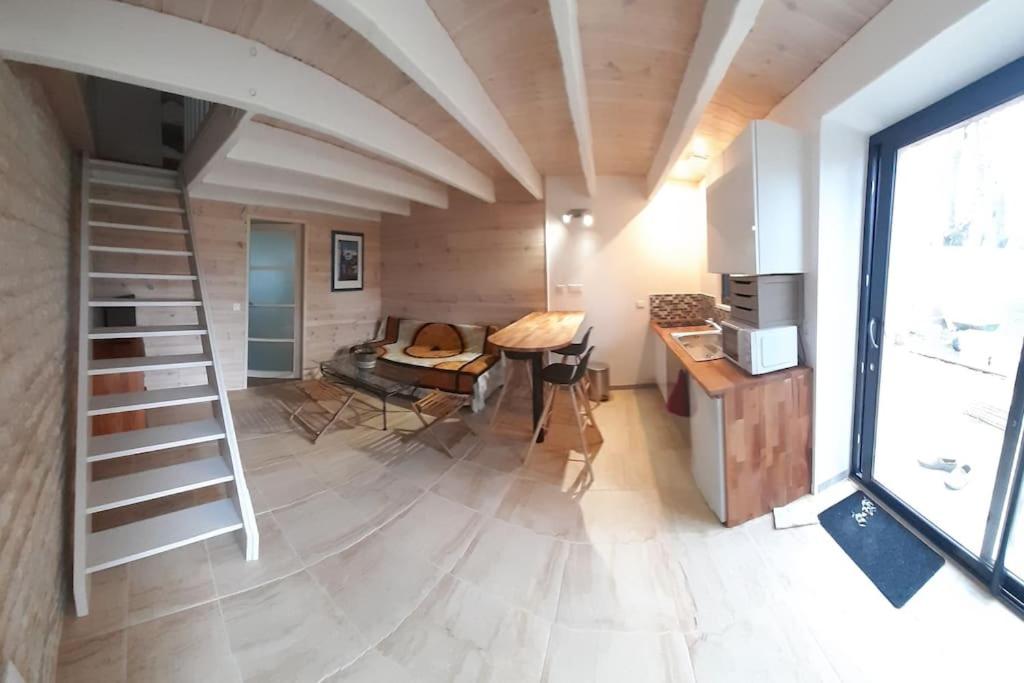 a room with a staircase and a table and a kitchen at Agréable gite au calme in Marigny