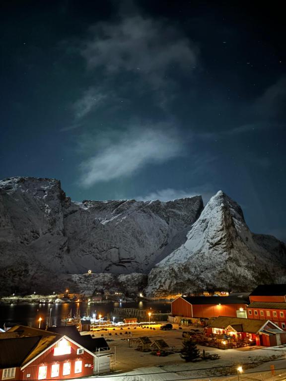 a town at night with a snow covered mountain at Reinebua in Reine