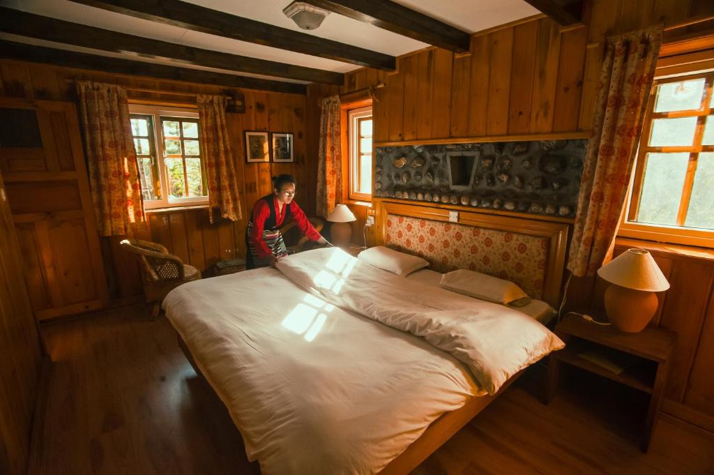 eine Person steht in einem Schlafzimmer mit einem großen Bett in der Unterkunft Mountain Lodges of Nepal - Phakding in Phakding