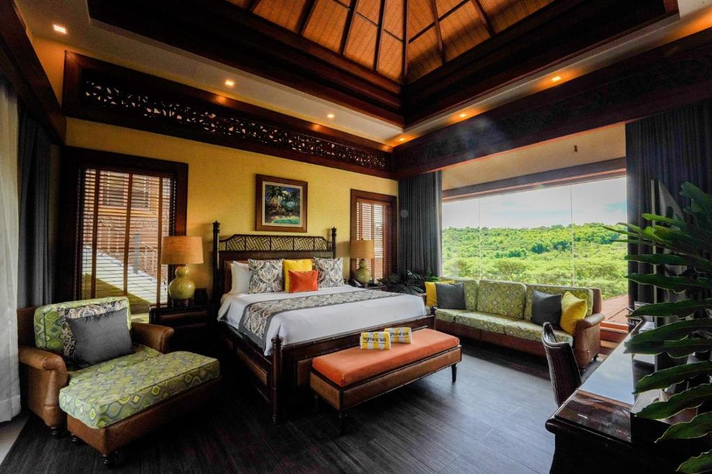 a bedroom with a bed and a couch and a window at Highland Bali Villas, Resort and Spa 