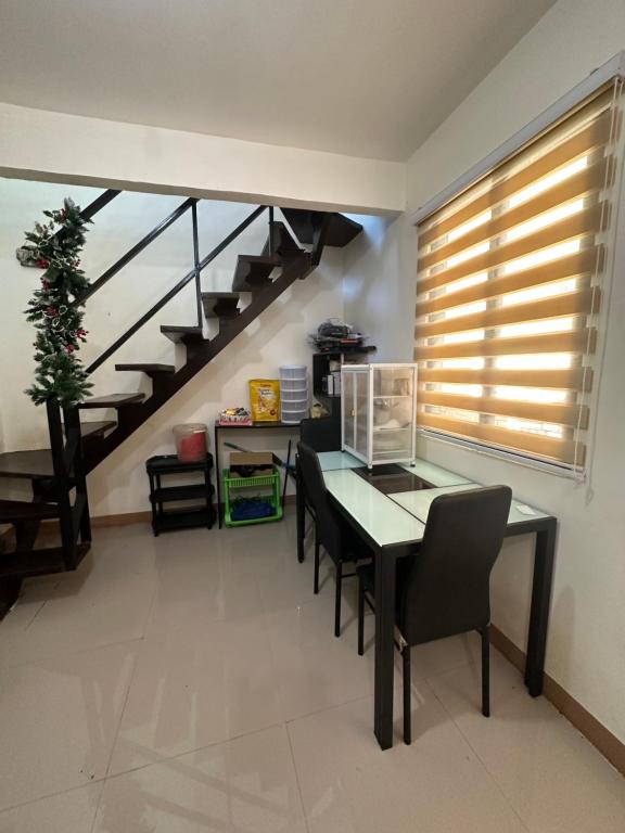a dining room with a table and chairs and a staircase at 3 Bedroom Apartment by Romz in Camaman
