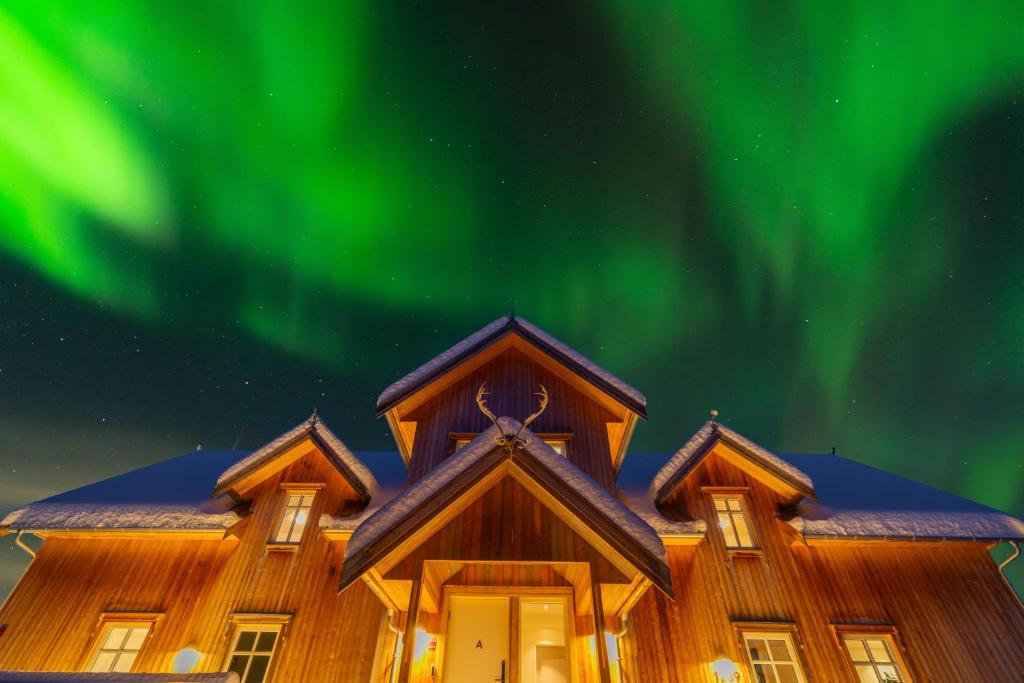 an enchanting house with the aurora in the sky at Villa Nestun - Northern lights villa with sauna in Selnes