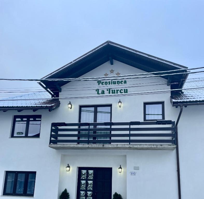 Ein weißes Gebäude mit einem Schild drauf. in der Unterkunft La Turcu in Văliug