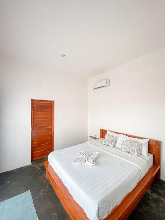 um quarto com uma grande cama branca com lençóis brancos em Turtle House Surf & Stay em Airsatang