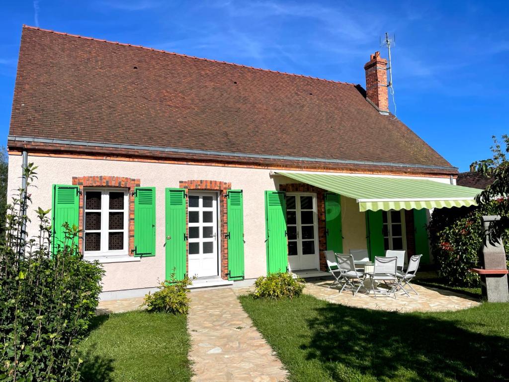 a white and green house with green shutters at Gîte du canal rue de la Tuilerie in Amilly