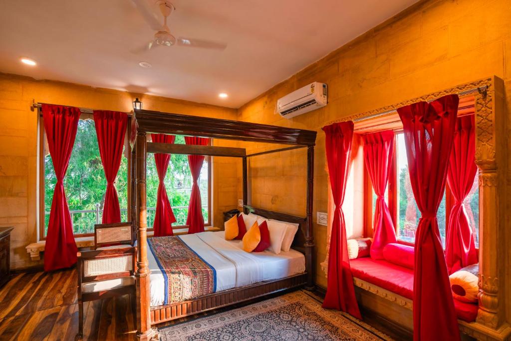 a bedroom with a canopy bed and red curtains at Hotel Helsinki House in Jaisalmer