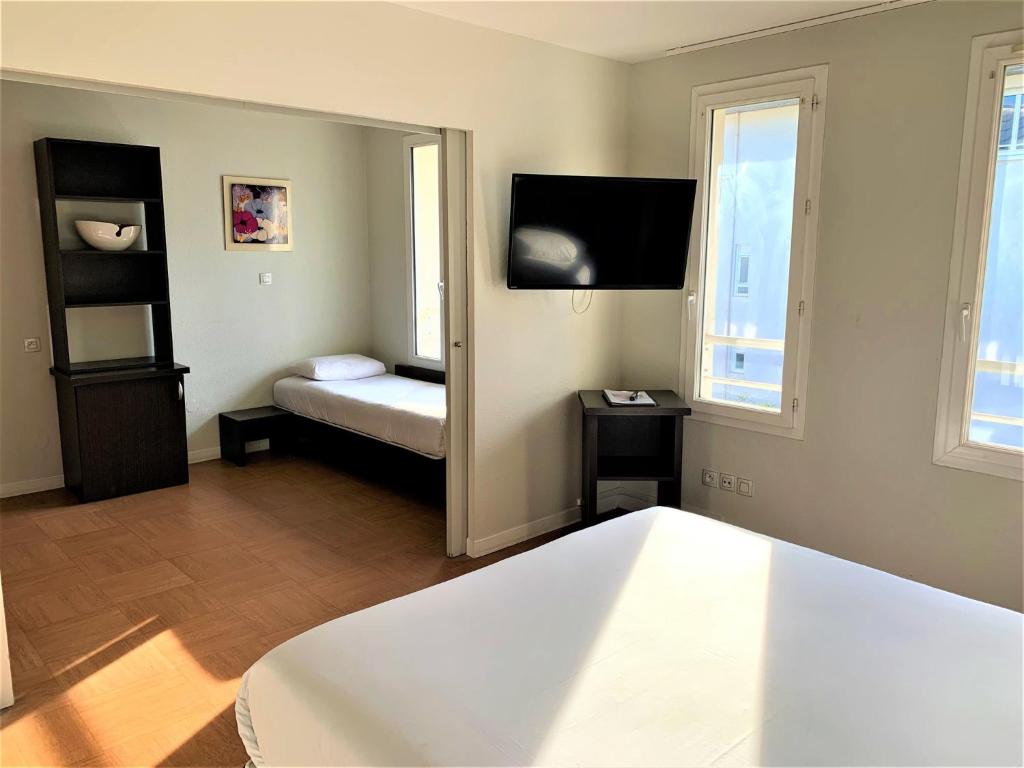 a bedroom with a bed and a mirror at ApartHotel Sainte-Marthe in Avignon