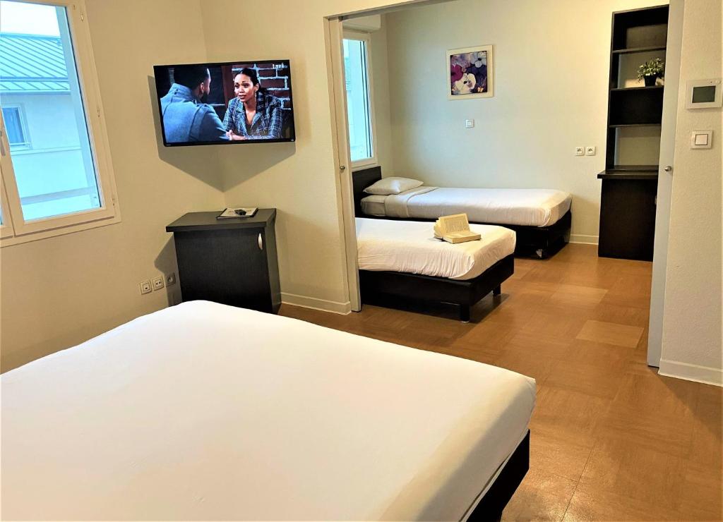 a room with two beds and a tv on the wall at ApartHotel Sainte-Marthe in Avignon
