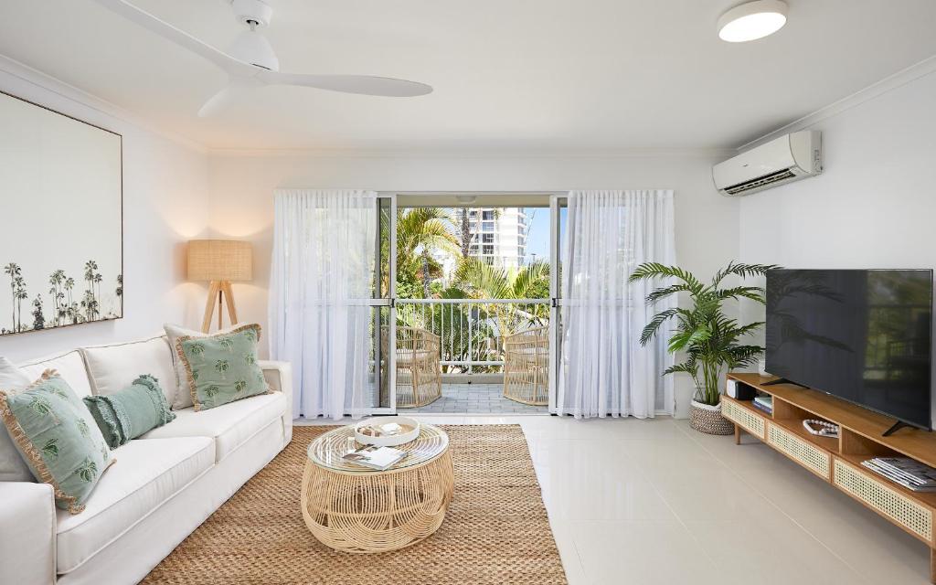 a living room with a white couch and a tv at Main Beach Coastal Apartment in Gold Coast