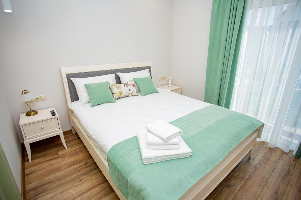 ベレホヴェにあるMy Home Apartの緑をアクセントにした白い大型ベッド付きのベッドルーム1室