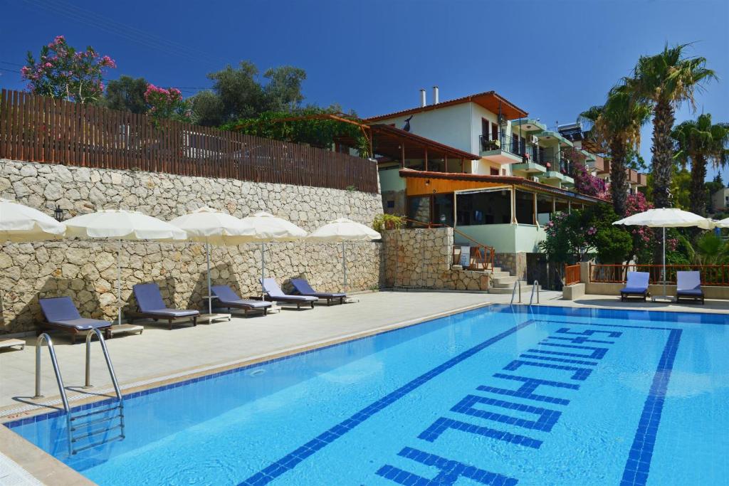 a swimming pool with chairs and umbrellas next to a building at Patara Delfin Hotel in Patara