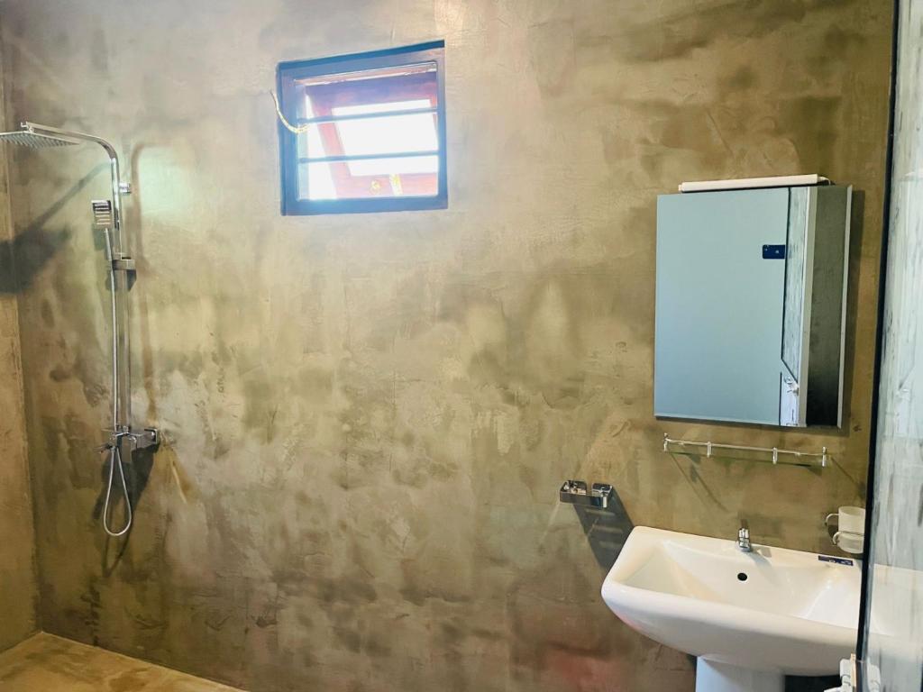un bagno con doccia, lavandino e specchio di Abhi Villa ad Ahangama