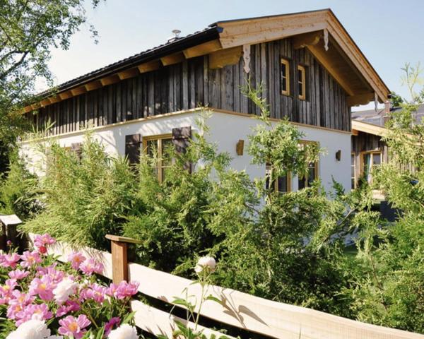 una casa con techo de madera y algunas flores en DIE ZWEI CHALETS AM TEGERNSEE "s' Gloane" & "s' Große" en Rottach-Egern
