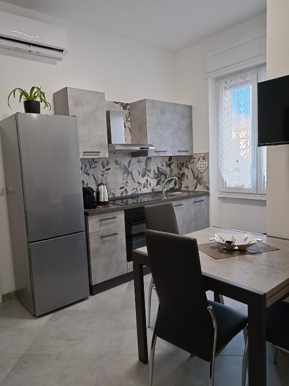 uma cozinha com uma mesa e um frigorífico de aço inoxidável em Orchidea Home em Busto Arsizio