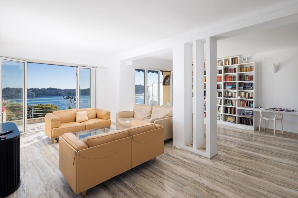 a living room with two couches and a table at Luxury Top Floor Sea View Apartment in Villefranche sur Mer in Villefranche-sur-Mer