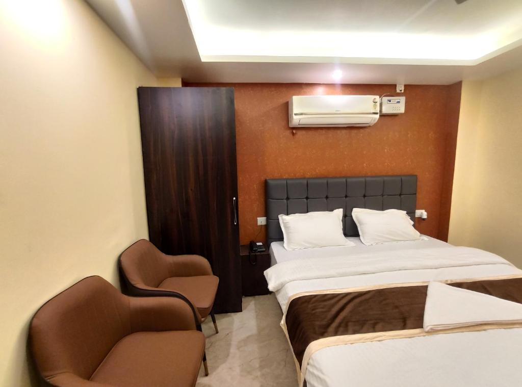 a hotel room with a bed and two chairs at Royal View Residency in Bodh Gaya