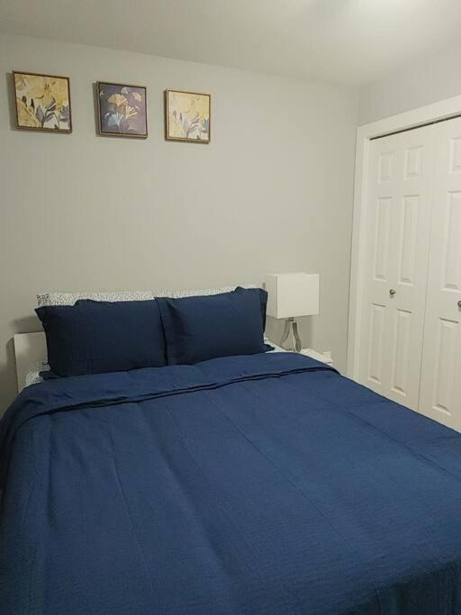 1 dormitorio con 1 cama azul y 2 cuadros en la pared en Oasis of Happiness en Saskatoon
