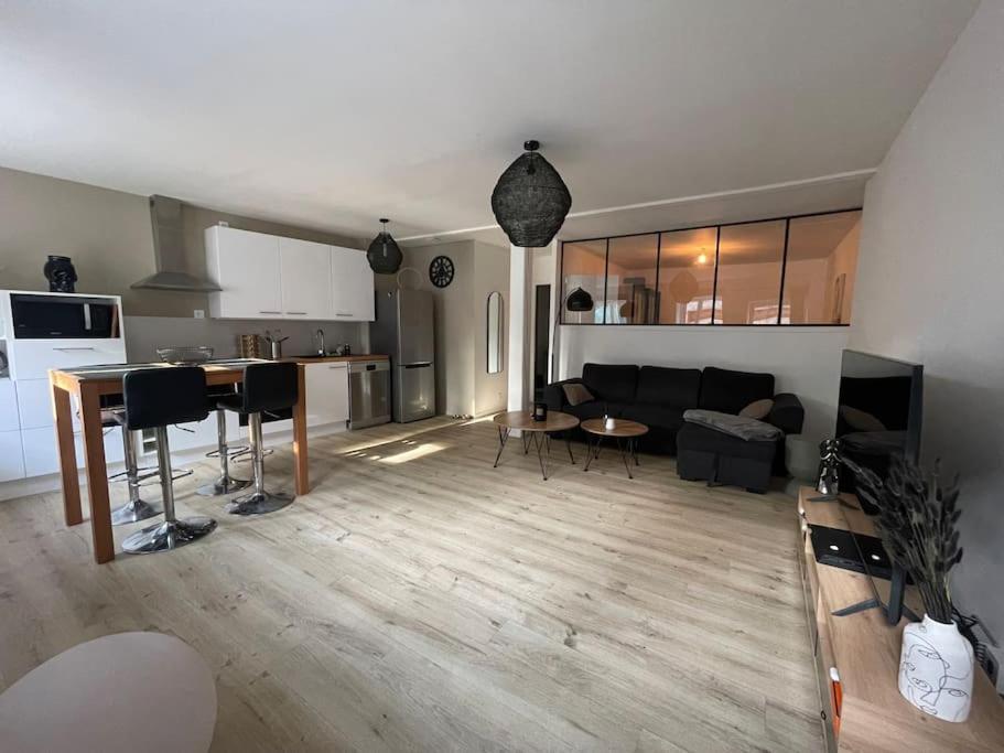 a living room and kitchen with a couch and a table at L'appartement charmant in Beynost