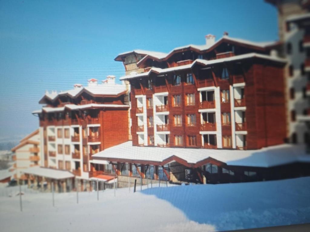 a large red building with snow on the ground at Apartment Wintermärchen Bansko 4* in Bansko