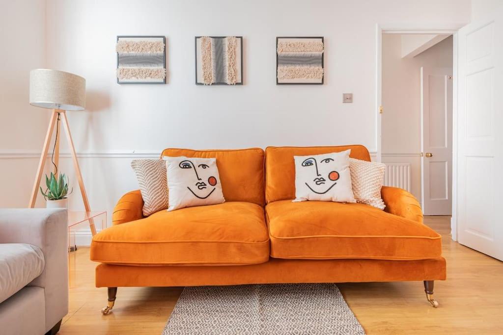 an orange couch with two pillows on it in a living room at Stunning 2BD Stay in Carlisle! in Carlisle