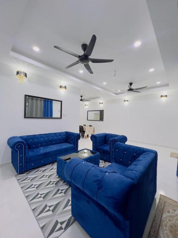 a living room with two blue couches and a ceiling fan at NOOR Homestay Paddy View in Kangar