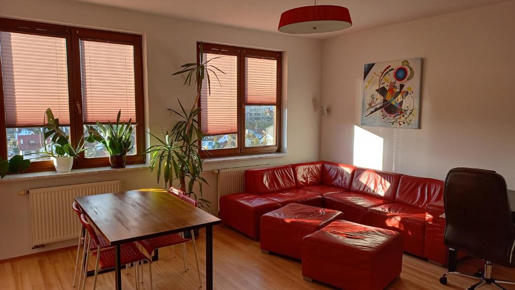 ワルシャワにあるBobrovia Apartmentのリビングルーム(赤いソファ、テーブル付)