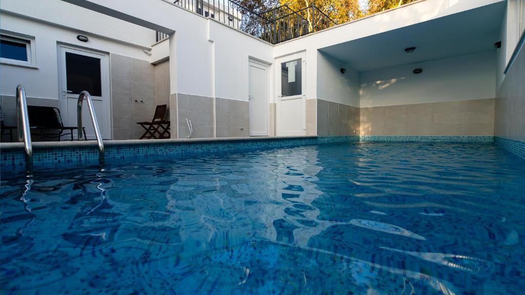 a swimming pool in a building with blue water at Guest house Lavanda 4 in Njivice