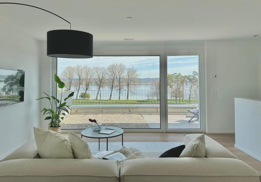 ein Wohnzimmer mit einem Sofa und einem großen Fenster in der Unterkunft Haus am Bodensee mit Sicht - Stilvoller Luxus in Ermatingen