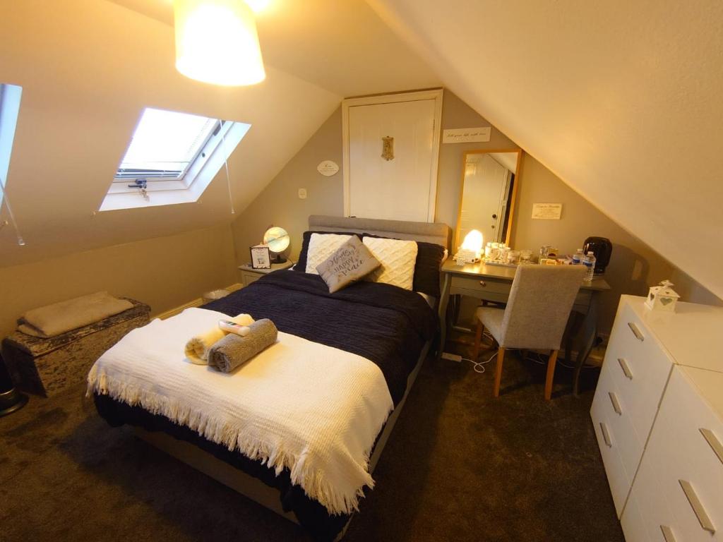Schlafzimmer mit einem Bett, einem Schreibtisch und einem Fenster in der Unterkunft Rose Garden Retreat in Rayleigh