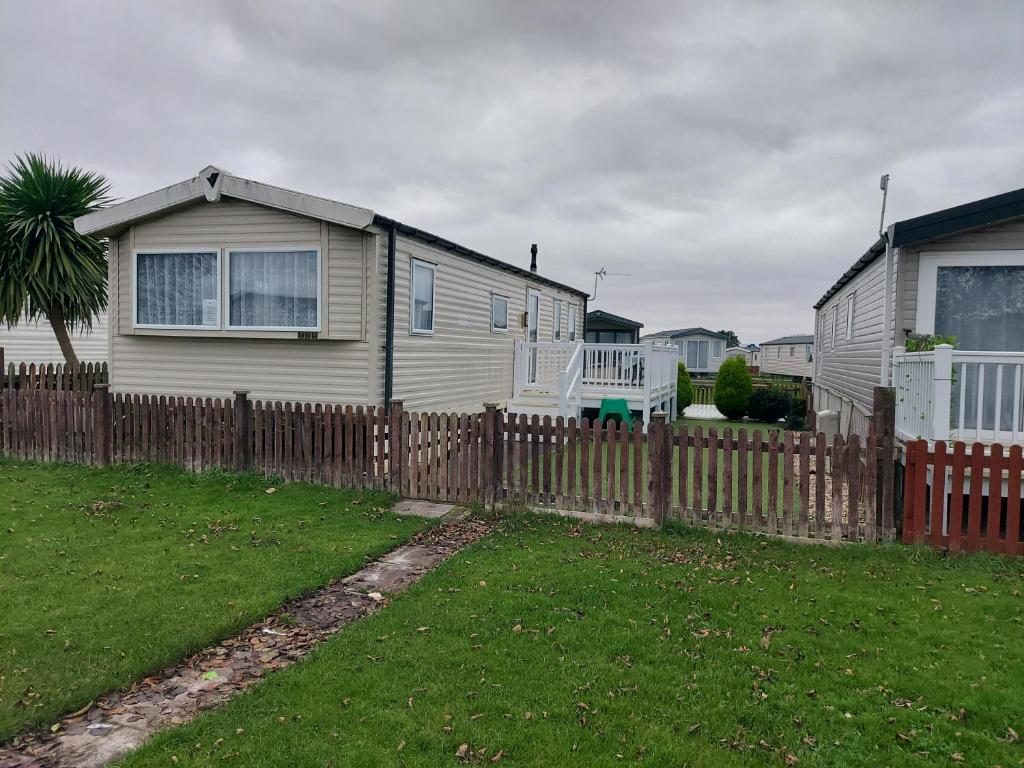 a house behind a wooden fence with a yard at 205 Holiday Resort Unity Pet friendly pass includ in Brean