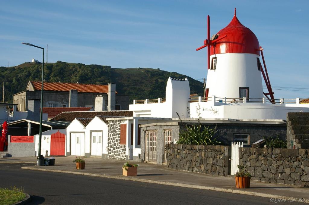 einem roten und weißen Leuchtturm und Gebäuden mit einer Straße in der Unterkunft Moinho Mó da Praia in Praia da Graciosa