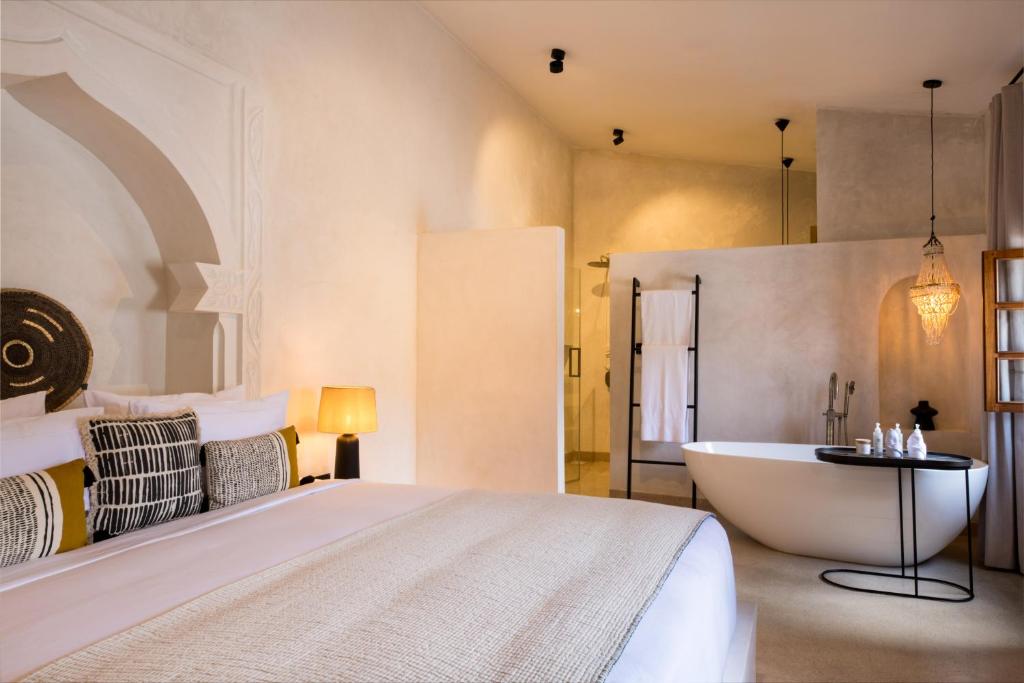 a bedroom with a large bed and a bath tub at The Neela Boutique Hotel Stone Town in Zanzibar City