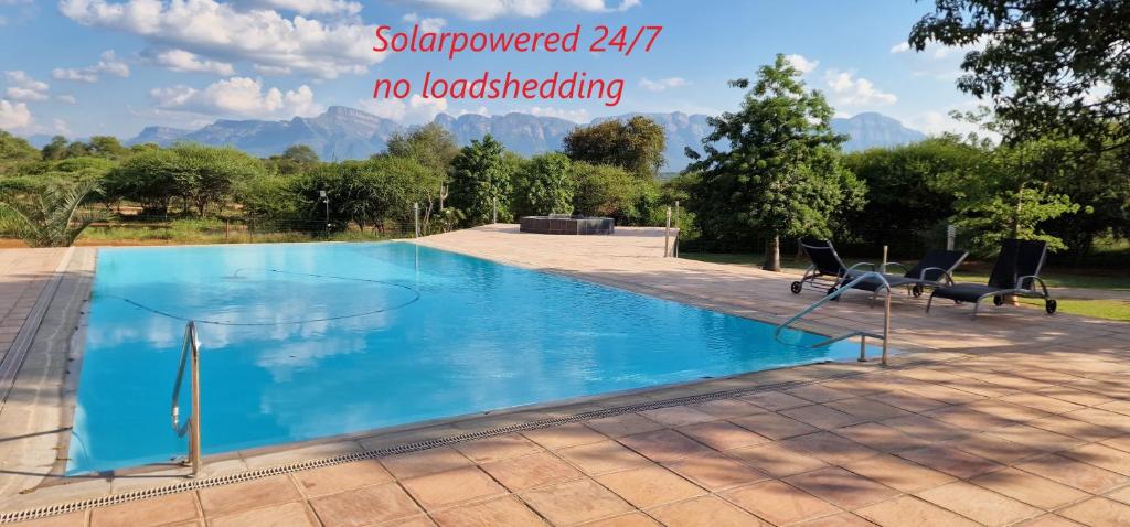 una grande piscina con due sedie accanto di Thandolwami Bushlodge & Spa a Hoedspruit