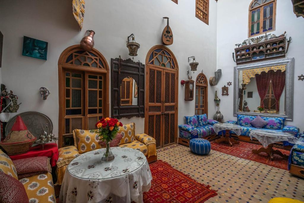una sala de estar con una mesa con un jarrón de flores. en Riad Les Idrissides, en Fez