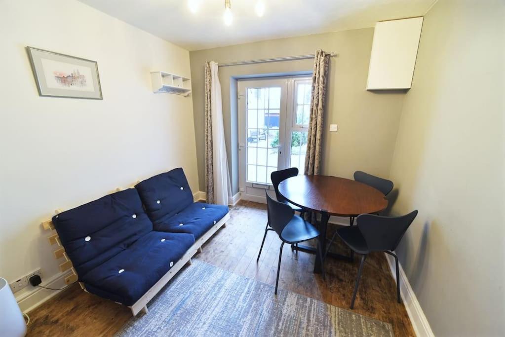 a living room with a blue couch and a table at Cosy Studio - Private Entrance Bishop’s Stortford in Bishops Stortford