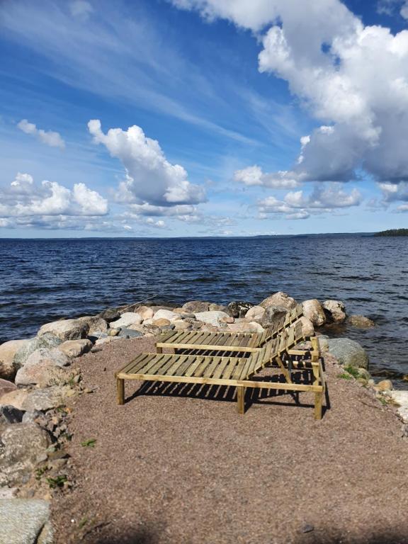 un banco de madera sentado en las rocas cerca del agua en Hamgården Nature Resort Tiveden en Tived