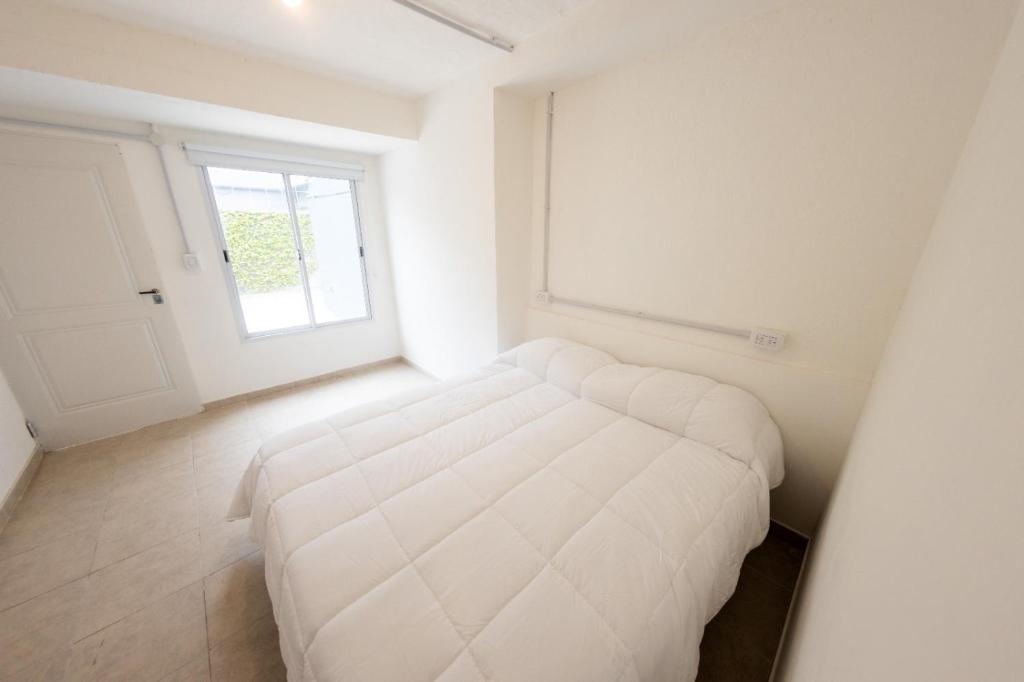 1 dormitorio con 1 cama blanca en una habitación con ventana en Petit apart, en Villa María