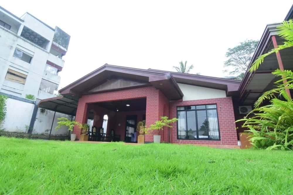 a house with a green lawn in front of it at CHANA BRICKS BUNGALOW in Ratnapura