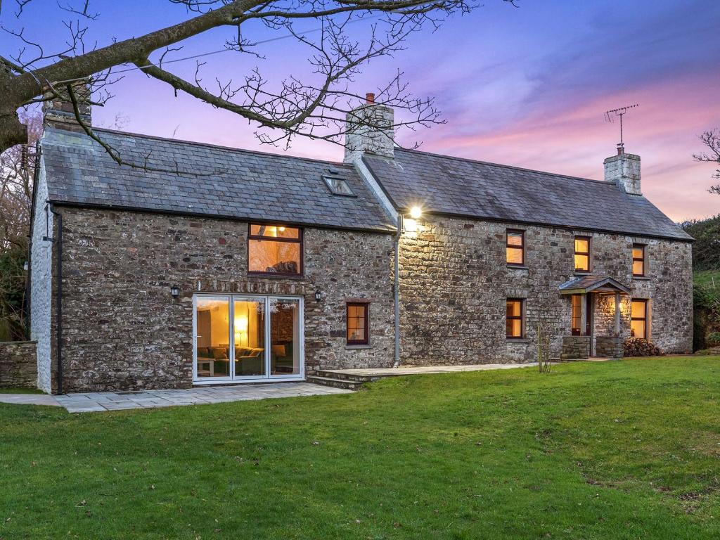 an old stone house with a lawn in front of it at Morfa Ganol in Llangranog